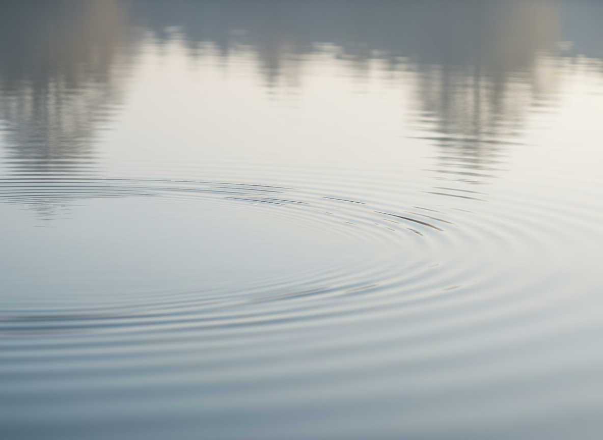 A calming and serene close-up of water ripples in soft blue and neutral tones, with gentle natural reflections and a minimal, tranquil feel suitable as a hero banner for a psychotherapy practice website.